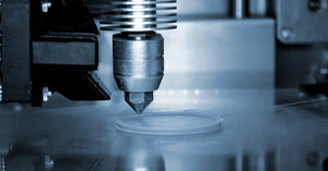A 3D printer nozzle, up close, extruding clear filament in a circular pattern to begin building a print.