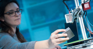 A young employee using her business’s commercial 3D printer to print various product designs in bulk.